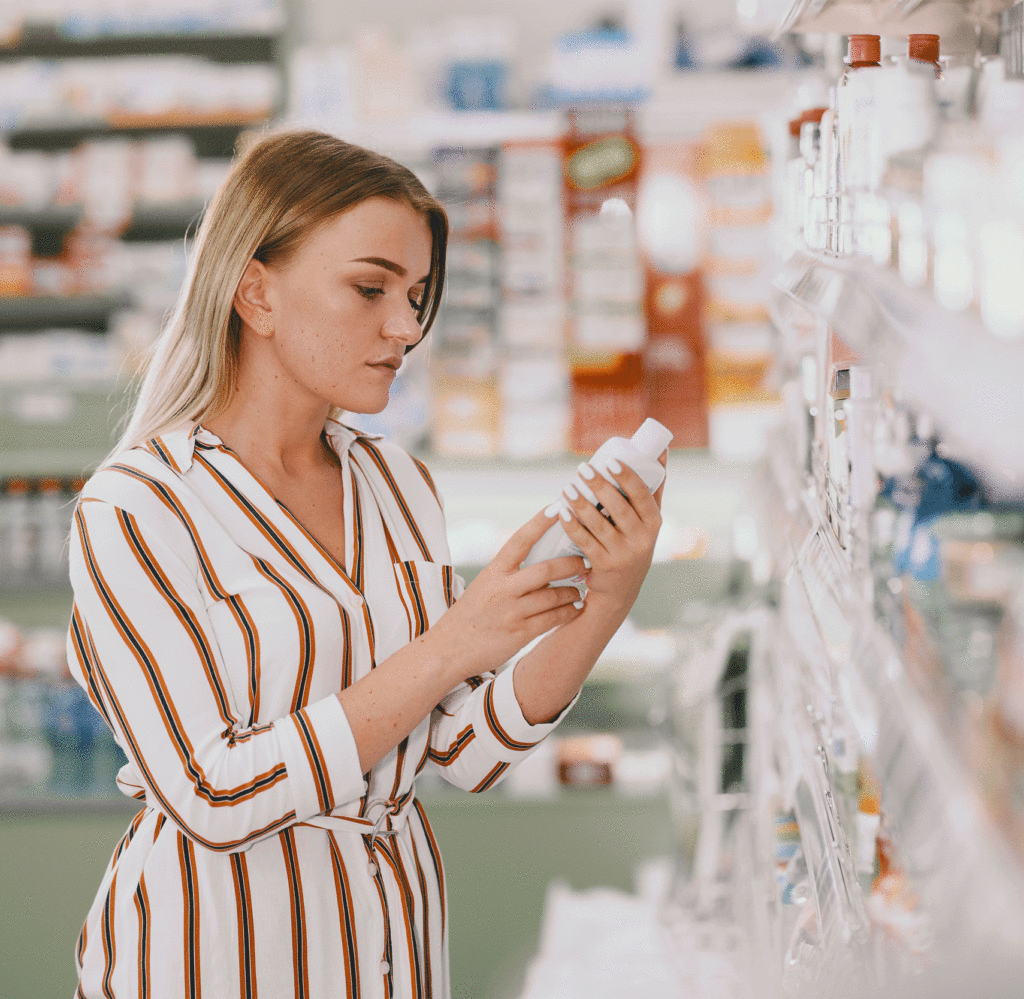 une femme inspecte l'étiquetage d'un complément alimentaire en pharmacie