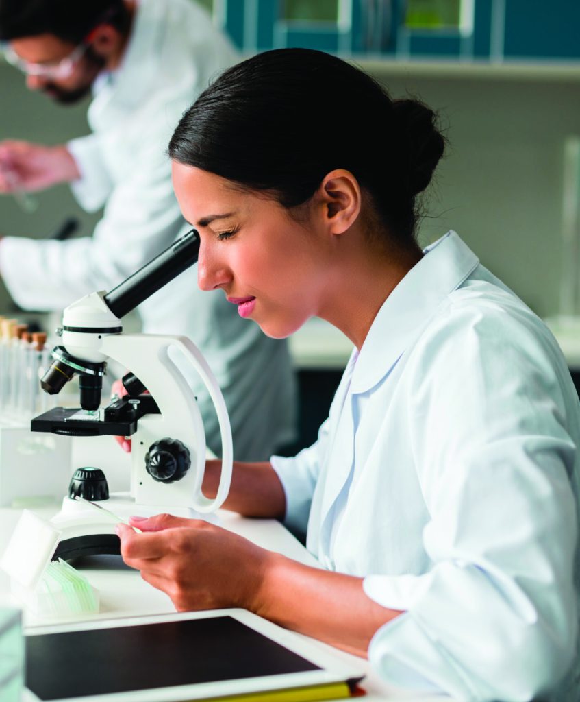 une scientifique regarde dans un microscope